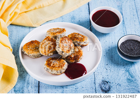 Small cottage cheese pancakes with poppy seeds on a plate on the table 131922487