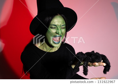 Woman in witch costume holding stuffed spider at Halloween party Woman in witch costume holding stuffed spider at Halloween party 131922967