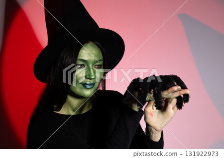Woman in witch costume holding black spider. 131922973