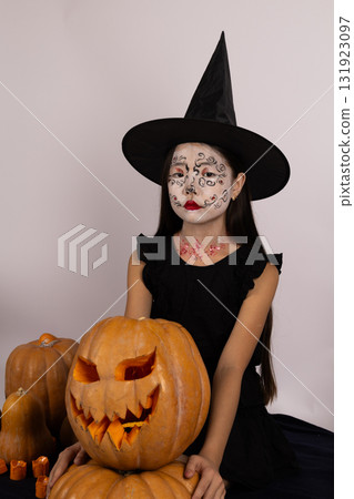 girl iholding a pumpkin, standing in front of a spooky decorated on Halloween girl iholding a pumpkin, standing in front of a spooky decorated on Halloween 131923097