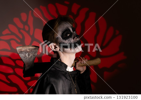 Young boy dressed as a vampire, his face bloody, in a spooky Halloween costume  131923100