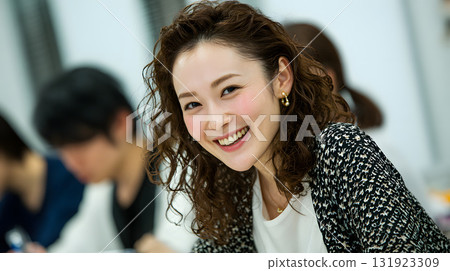 A smiling woman in her 30s attending a lecture in a classroom 131923309