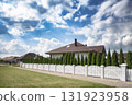 Blurred view of a quiet suburban neighborhood with private houses, white fences, and a curved street under a cloudy sky. Background for real estate, property, and urban development themes. 131923958