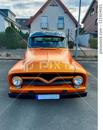 Classic orange vintage truck parked outside a charming residential neighborhood during a sunny day 131924081