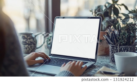 Woman Typing on Laptop with Blank Screen in Cozy Office Workspace for Mockups and Promotional Use 131924212