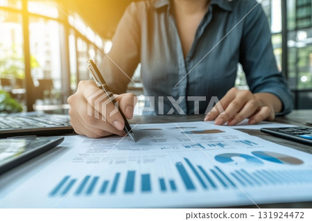 Female Financial Analyst Reviewing Stock Market Reports and Charts in a Modern Office Setting 131924472