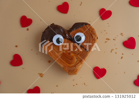 April fool day funny creative eyes on Delicious fresh croissant topped with Dark chocolate flavor Ganache. Creation unique heart shape bakery. Puff pastry holiday love gift present idea Valentine's 131925012