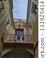 Architectural view of a historic building with colorful flags hanging from a balcony, showcasing intricate design elements and a vibrant atmosphere in a charming urban setting 131925414