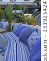 Cozy outdoor seating area featuring blue patterned cushions and lush greenery, creating a serene atmosphere for relaxation and social gatherings in a stylish environment 131925424