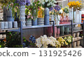 Colorful display of various flower arrangements in decorative vases on shelves, showcasing vibrant floral designs and textures in a modern retail environment 131925426