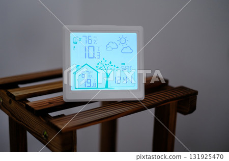 A digital weather station and thermometer displayed in a cozy home environment A digital weather station and thermometer displayed in a cozy home environment 131925470