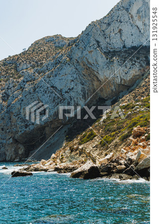 Beautiful coastal landscape with rugged cliffs and clear blue waters during a sunny afternoon Beautiful coastal landscape with rugged cliffs and clear blue waters during a sunny afternoon 131925548