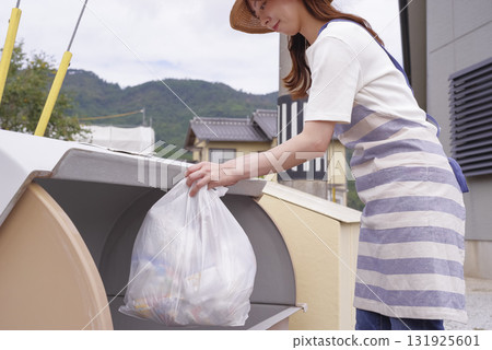 一名繫著圍裙的婦女正在清理家庭垃圾 131925601