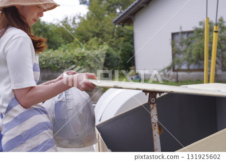 一名繫著圍裙的婦女正在清理家庭垃圾 131925602