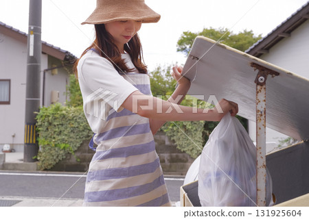 A woman in an apron taking out household garbage A woman in an apron taking out household garbage 131925604