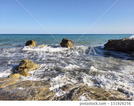 A tranquil seascape showcasing beautiful rocks and waves under a pristine clear blue sky 131926256