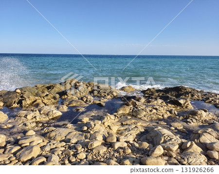 A picturesque and scenic Rocky Beach accompanied by clear blue ocean waves rolling in gracefully A picturesque and scenic Rocky Beach accompanied by clear blue ocean waves rolling in gracefully 131926266