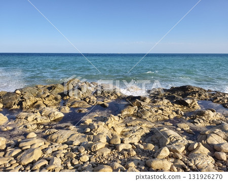 Experience the serene coastal view showcasing beautiful rocks alongside calm waters 131926270