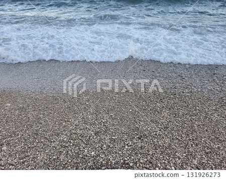 Gentle waves lap softly on the pebble beach during a beautiful sunset over the horizon 131926273