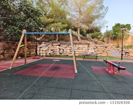 A Colorful Playground featuring a Swing and a Seesaw situated under a Clear Blue Sky 131926308