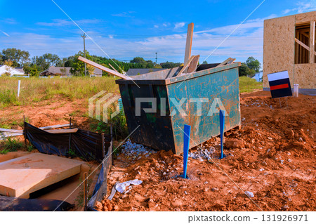 Debris container sits at construction site surrounded by earth building materials under works day Debris container sits at construction site surrounded by earth building materials under works day 131926971