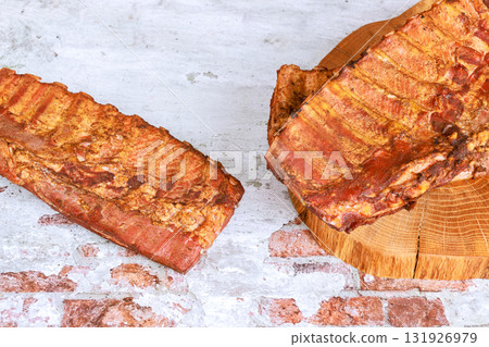 Grilled smoked flavorful ribs sit on wooden board, juicy, flavorful dish perfect for an outdoor barbecue. Grilled smoked flavorful ribs sit on wooden board, juicy, flavorful dish perfect for an outdoor barbecue. 131926979