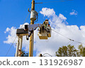 Utility electrical worker in bucket lifts to repair power lines on tall wooden pole under works day 131926987
