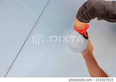 Electrician installing new light during work day in apartment room 131927015