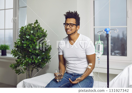 Happy young African American man receiving an intravenous vitamin infusion at the clinic Happy young African American man receiving an intravenous vitamin infusion at the clinic 131927342