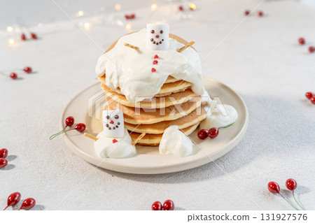 Snowman and stack of pancakes on white background 131927576