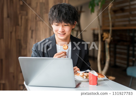 商人/男人在自助餐廳/咖啡館吃午餐時看著電腦 131927783
