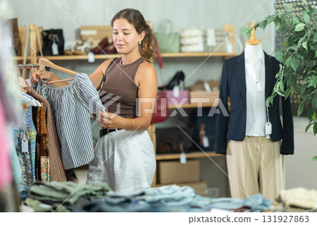 Young woman choosing lazy clothes in boutique Young woman choosing lazy clothes in boutique 131927863