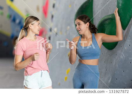 Two womens in climbing gym hall, having nice conversation before training, discussing workout plan and sharing fitness tips Two womens in climbing gym hall, having nice conversation before training, discussing workout plan and sharing fitness tips 131927872
