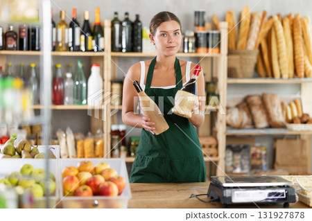 Female salesperson offers to buy bottle of wine in liquor department of grocery supermarket 131927878