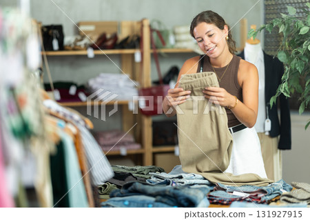 Woman standing near shelves with pants in a store 131927915