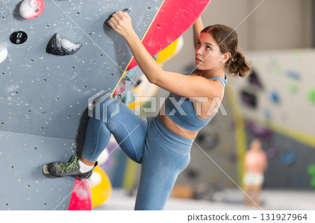 Girl climbs artificial wall bouldering, working out in gym 131927964