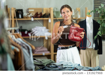 Girl customer choose handbag in store, and buyer carefully examines product. Girl customer choose handbag in store, and buyer carefully examines product. 131927988