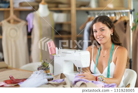 Female dressmaker working on sewing machine in workshop Female dressmaker working on sewing machine in workshop 131928005