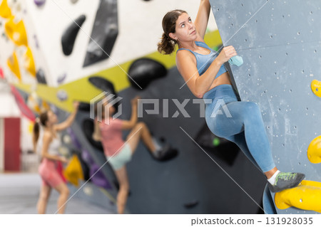 Woman exercising on wall in climbing gym during bouldering training 131928035