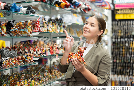Young woman looking at bull figurine at souvenir market Young woman looking at bull figurine at souvenir market 131928113