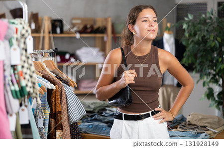 Girl is intently examining sales area of womens clothing store and looking for something 131928149