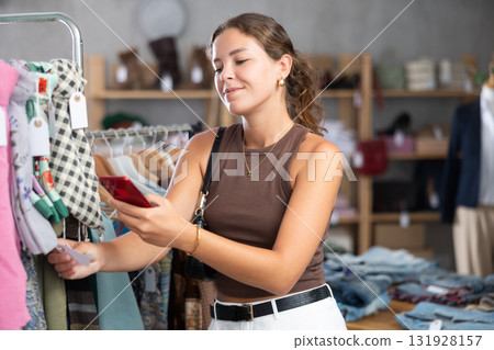 While shopping, girl scans barcode on label of scarf While shopping, girl scans barcode on label of scarf 131928157