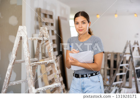 Portrait of woman filling documentation during repair works in construction site 131928171