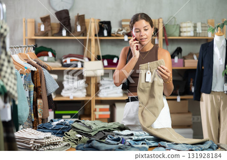 woman calls on the phone and holds her pants in her hands woman calls on the phone and holds her pants in her hands 131928184
