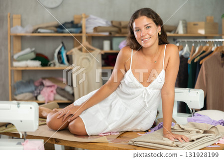 Woman playfully sitting on a table in a workshop Woman playfully sitting on a table in a workshop 131928199