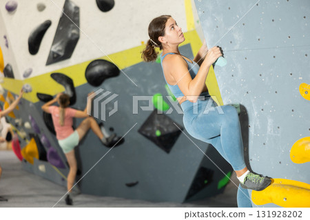 Woman exercising on wall in climbing gym during bouldering training 131928202