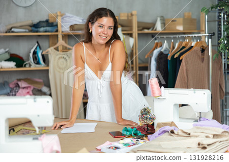 Dressmaker draws a model of clothes on paper in a workshop 131928216