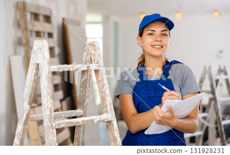 Positive woman builder with documents during repair works 131928231