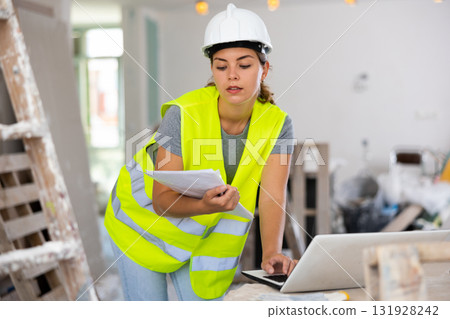 Female architect using laptop during repair works Female architect using laptop during repair works 131928242