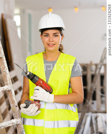 Female foreman in protective yellow vest and hard hat with screwdriver in hand Female foreman in protective yellow vest and hard hat with screwdriver in hand 131928268
